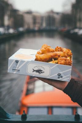 Fish & Fries boven een Amsterdamse gracht met een oranje rondvaartboot