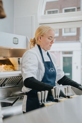 Medewerkster bereidt bestellingen voor aan het roestvrijstalen werkblad
